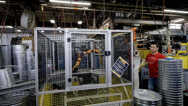 Employee works near cobot in safety cage